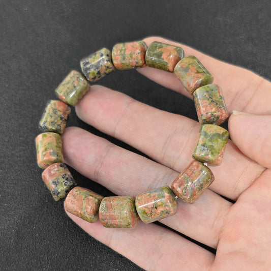 natural unakite 14x10mm barrel bead gemstone bracelet held in hand showing pink and green epidote matrix