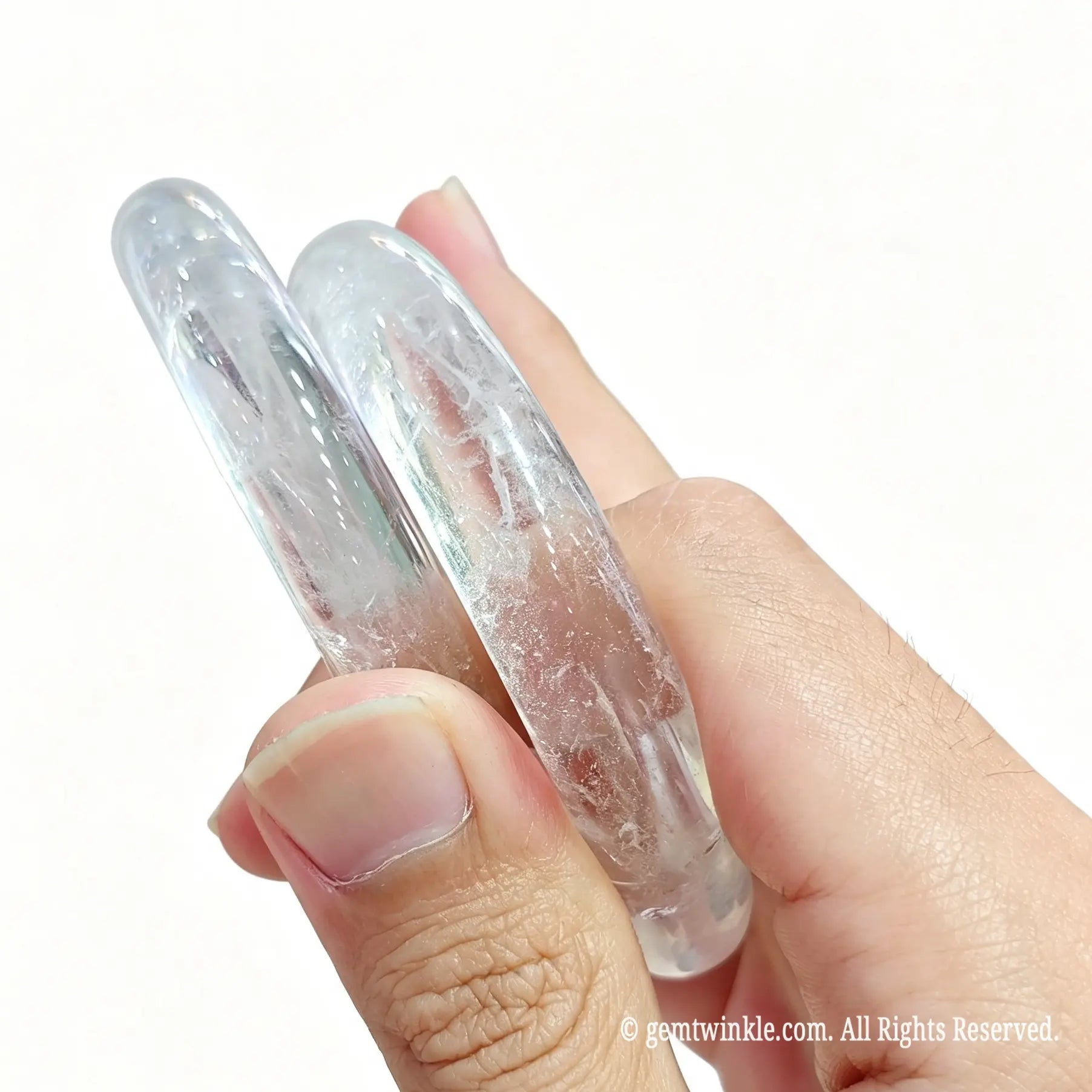 Pair of natural clear white quartz bangles held in hand displaying subtle ice inclusions