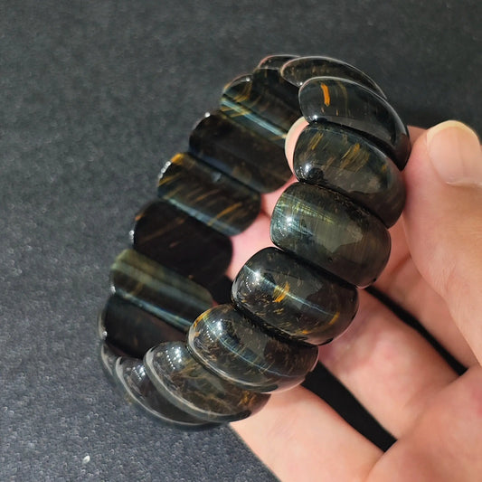natural yellow blue tigers eye 22x14mm crescent moon bead bracelet held in hand showcasing chatoyancy