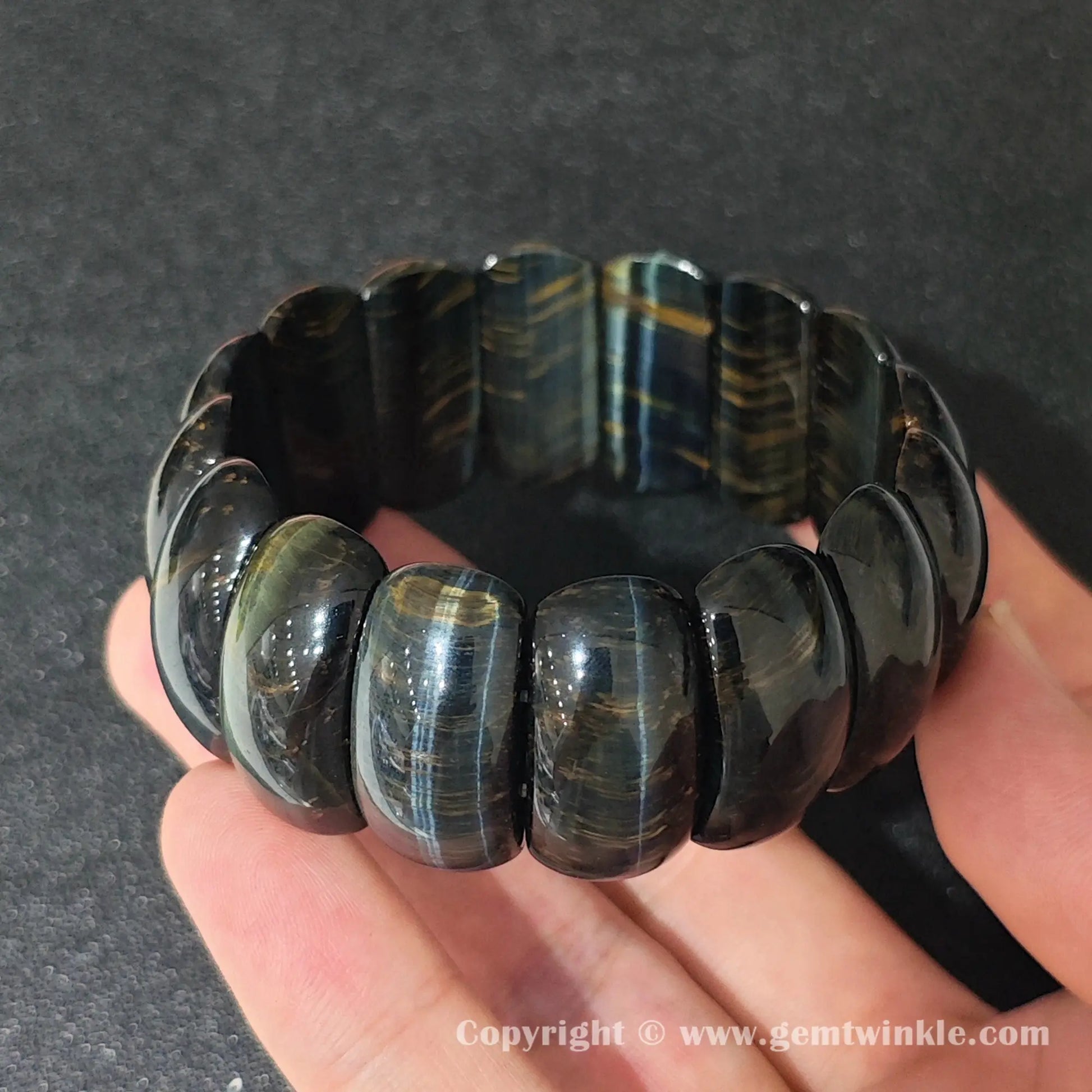 natural yellow blue tigers eye crescent plate bracelet displayed over palm highlighting glossy polish