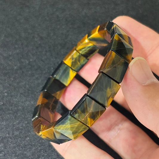 natural yellow blue tigers eye 10x10mm square pyramid bracelet held in hand showing chatoyancy