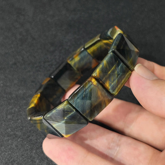 natural yellow blue tigers eye square pyramid bracelet held in hand showcasing golden and blue chatoyancy