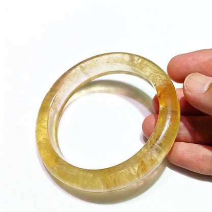 Natural yellow fluorite bangle handpicked solid gemstone bracelet held in hand showing translucent honey gold luster