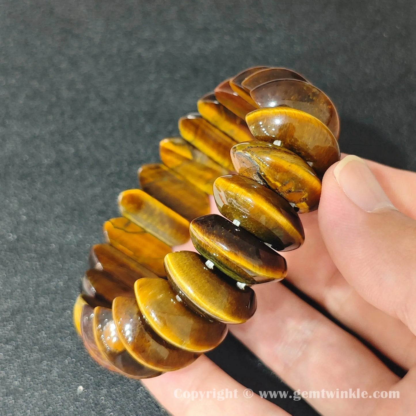 close up of golden yellow tigers eye crescent beads displaying chatoyant light flash
