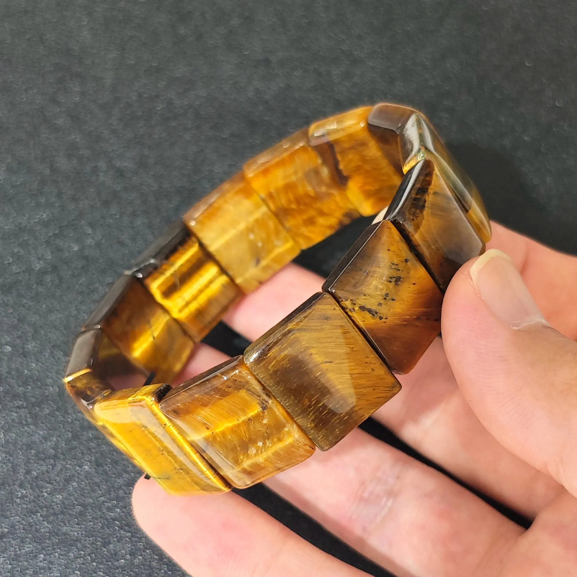 natural yellow tigers eye plate cuff bracelet held in hand showing golden brown rectangular beads