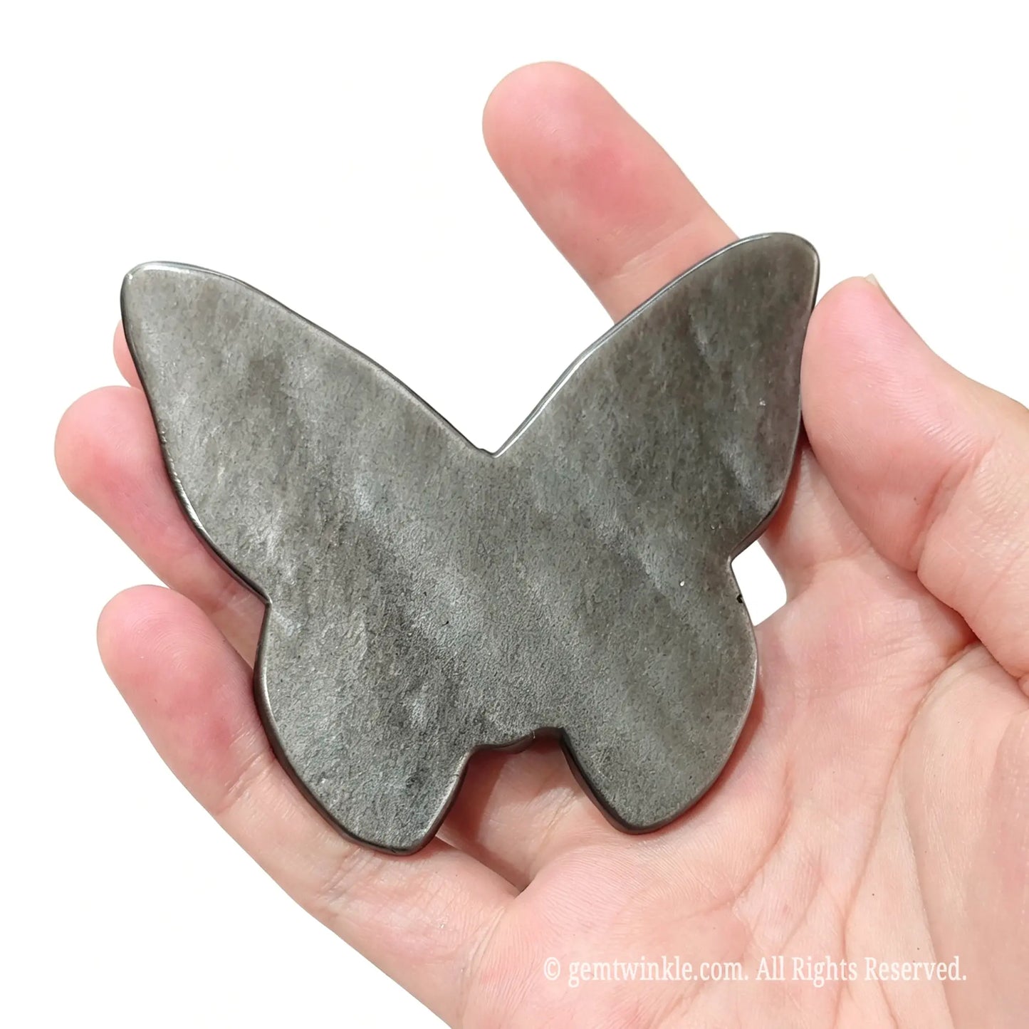 Hand holding silver sheen obsidian skull butterfly showing smooth polished flat back surface