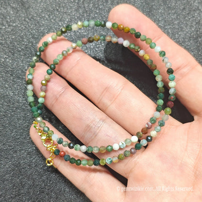 Hand holding 3mm faceted ocean jasper necklace revealing multicolored orbicular chalcedony patterns