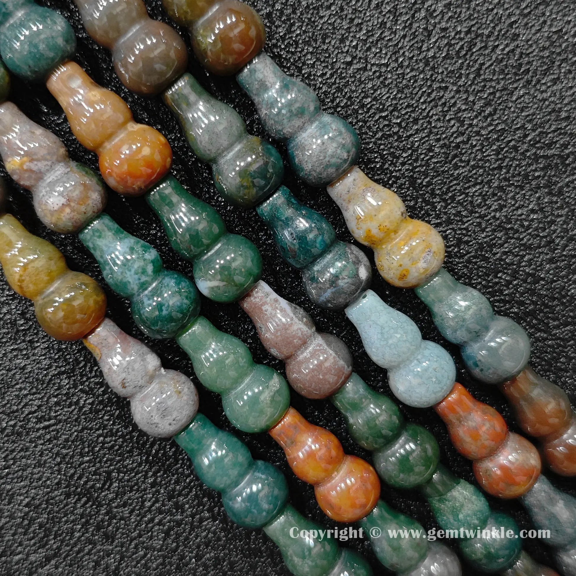 Natural ocean jasper bottle gourd bead strand held over hand for size scale