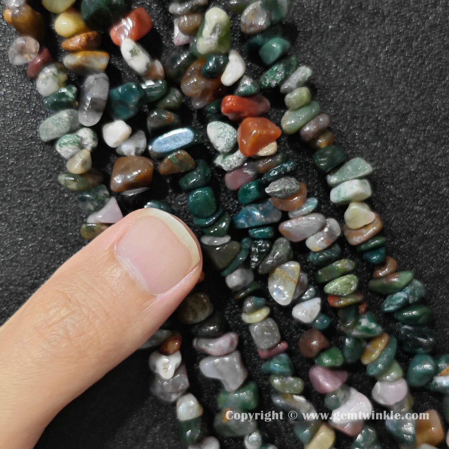 Natural ocean jasper chip bead strand held over hand showing size scale