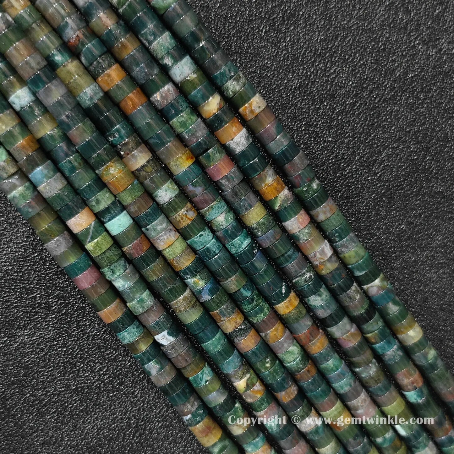 Close up view of 6x3mm ocean jasper disc rondelle beads inspected on fingers for quality preview