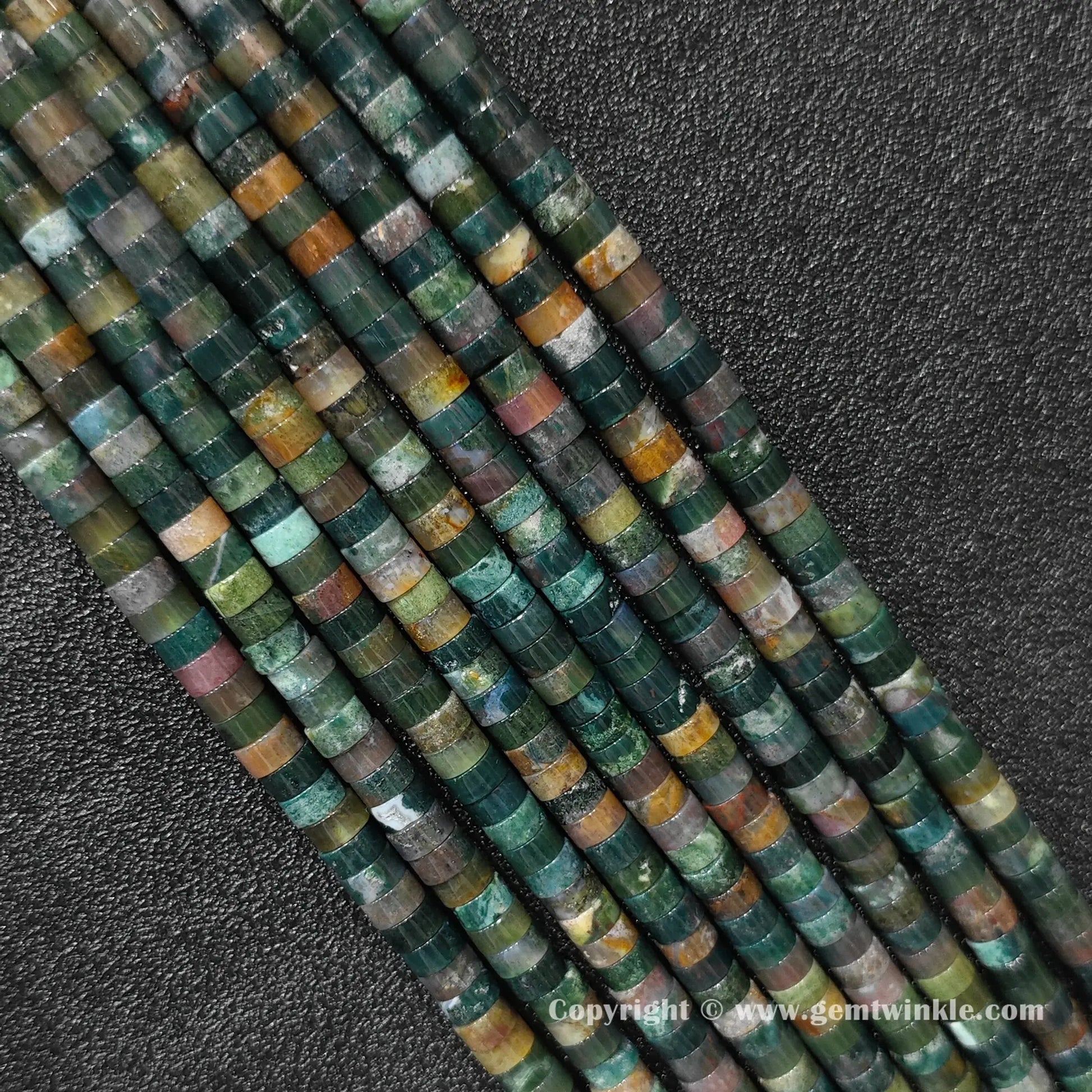 Close up view of 6x3mm ocean jasper disc rondelle beads inspected on fingers for quality preview
