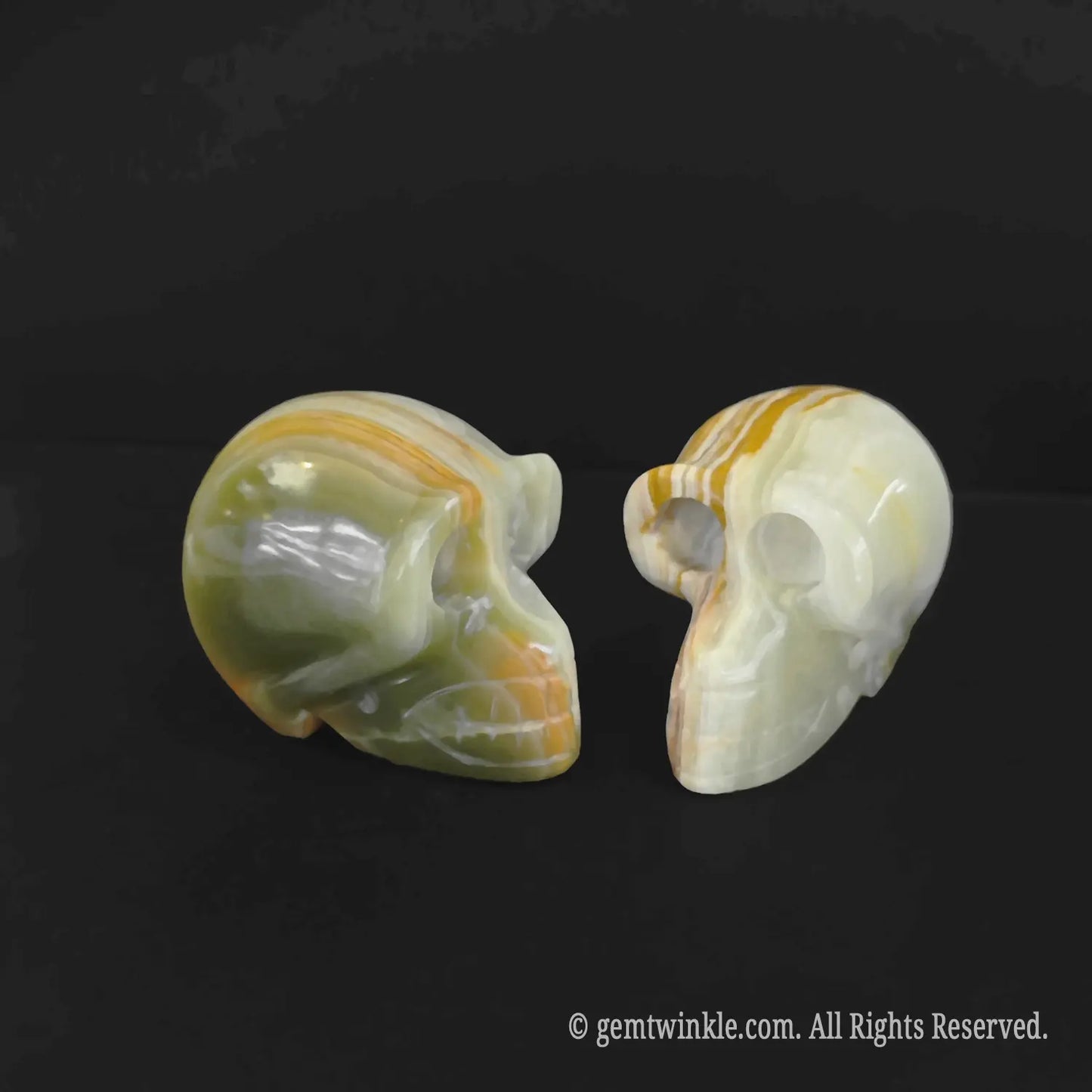Side angle of two 6cm ocean jasper human skulls showing detailed cheekbones and green color banding