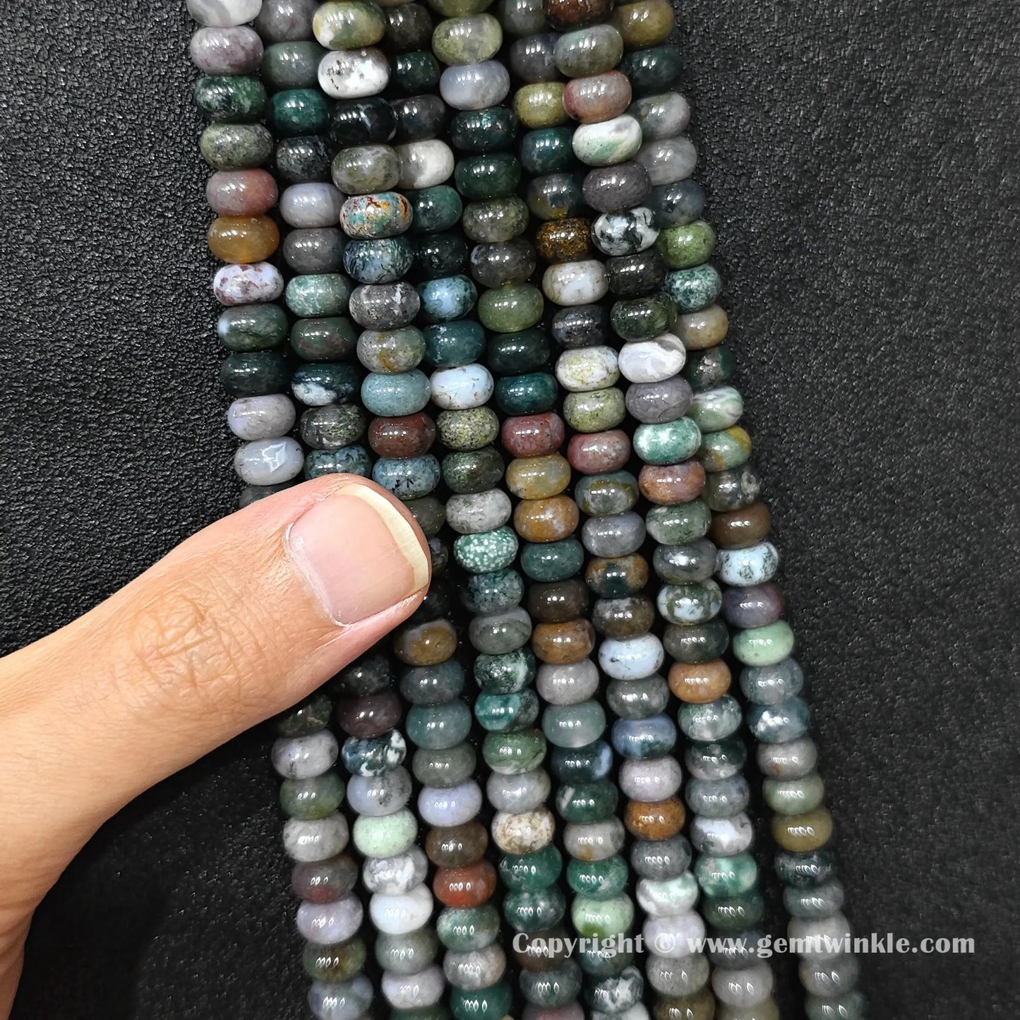 Close up view of 8x6mm ocean jasper smooth disc rondelle beads inspected on fingers for quality preview