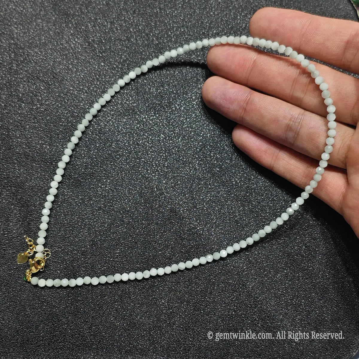 Hand holding 3mm micro faceted green angelite necklace strand showing solid opaque milky mint color