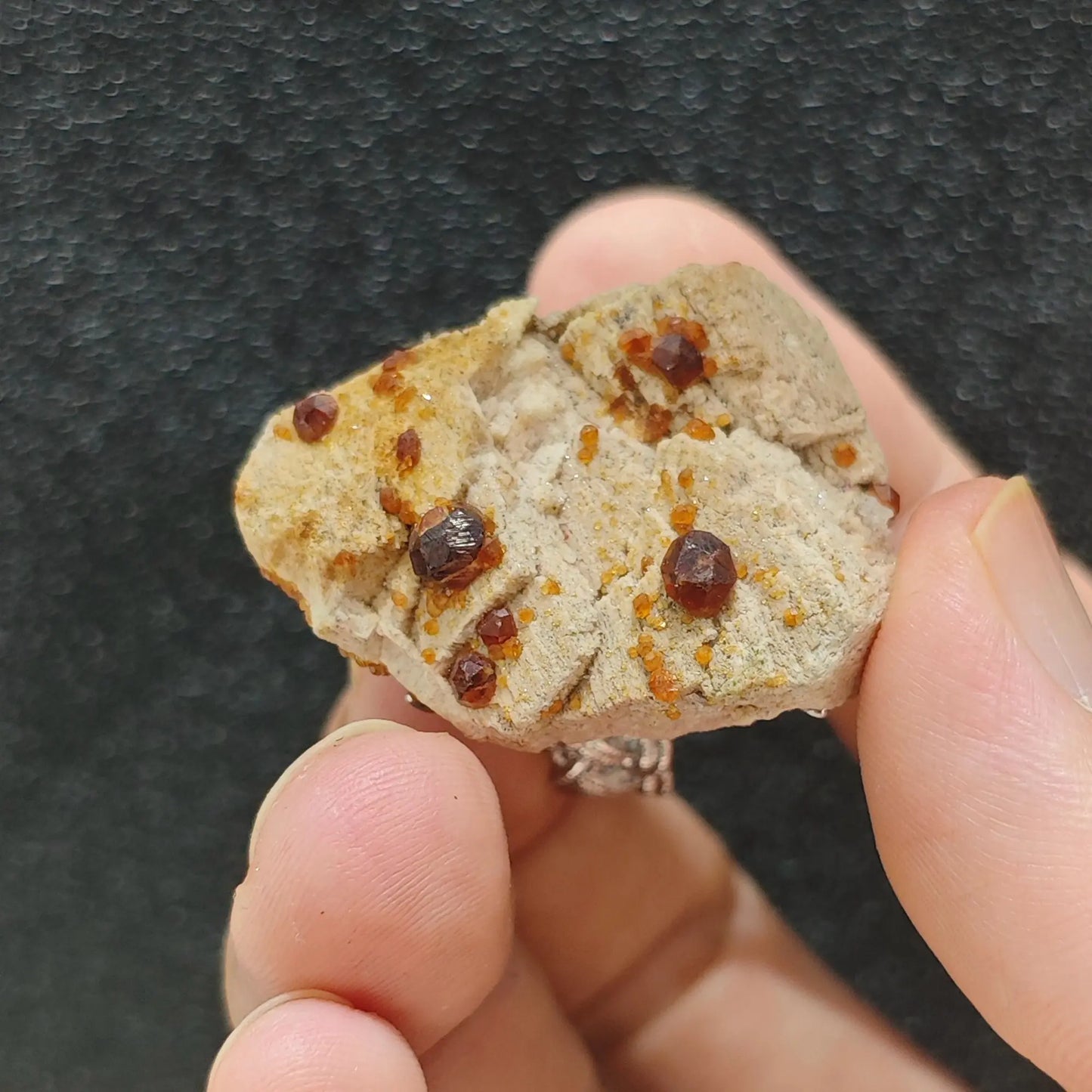 Organic raw garnet stone slice ring bottom view resting in hand showing natural rock backing and secure setting
