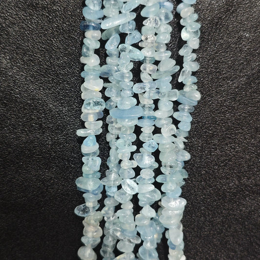 Close up of multi strands of acid-washed aquamarine 5-10mm irregular light blue chips