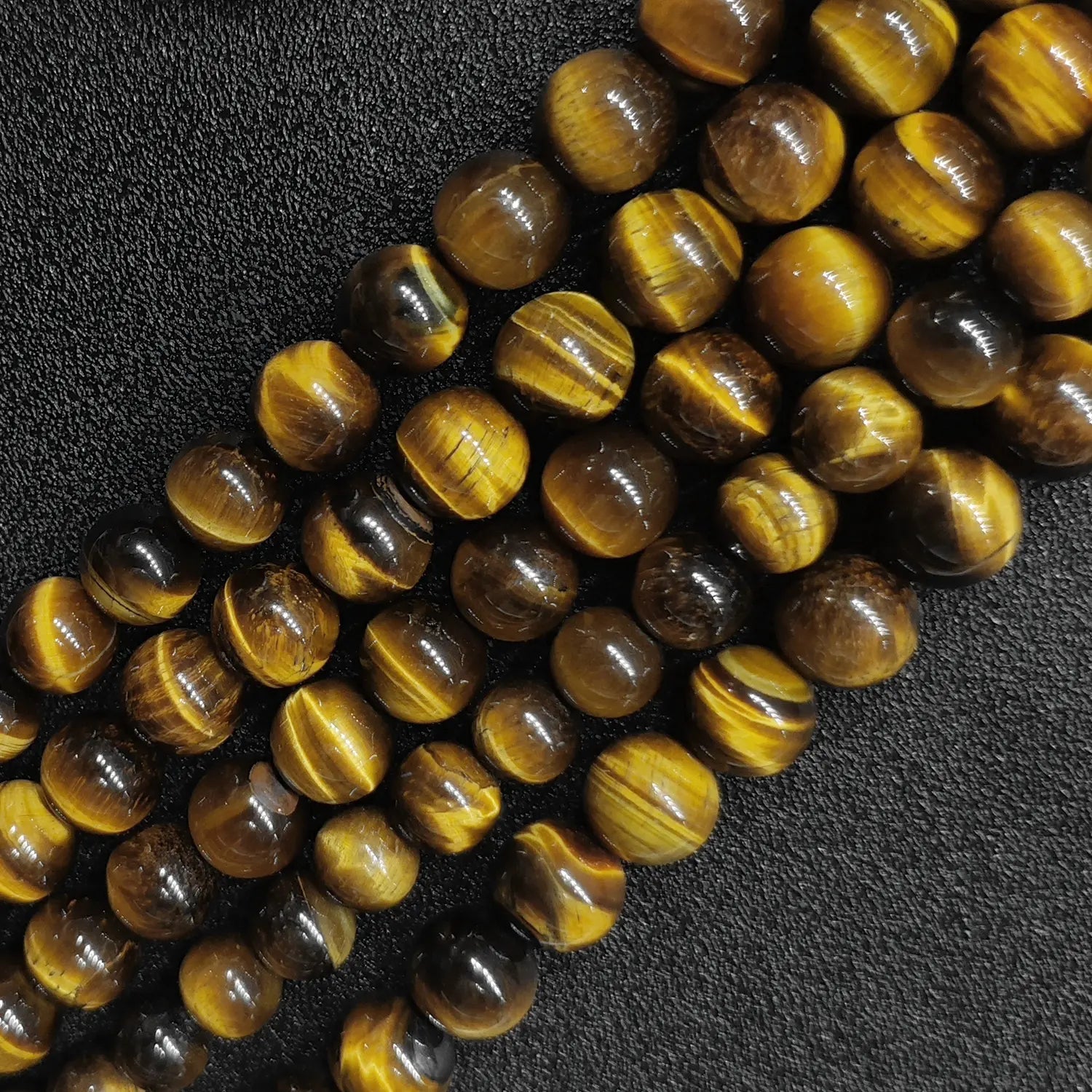 Close up of B plus grade yellow tigers eye round beads showing smooth surface and golden chatoyancy