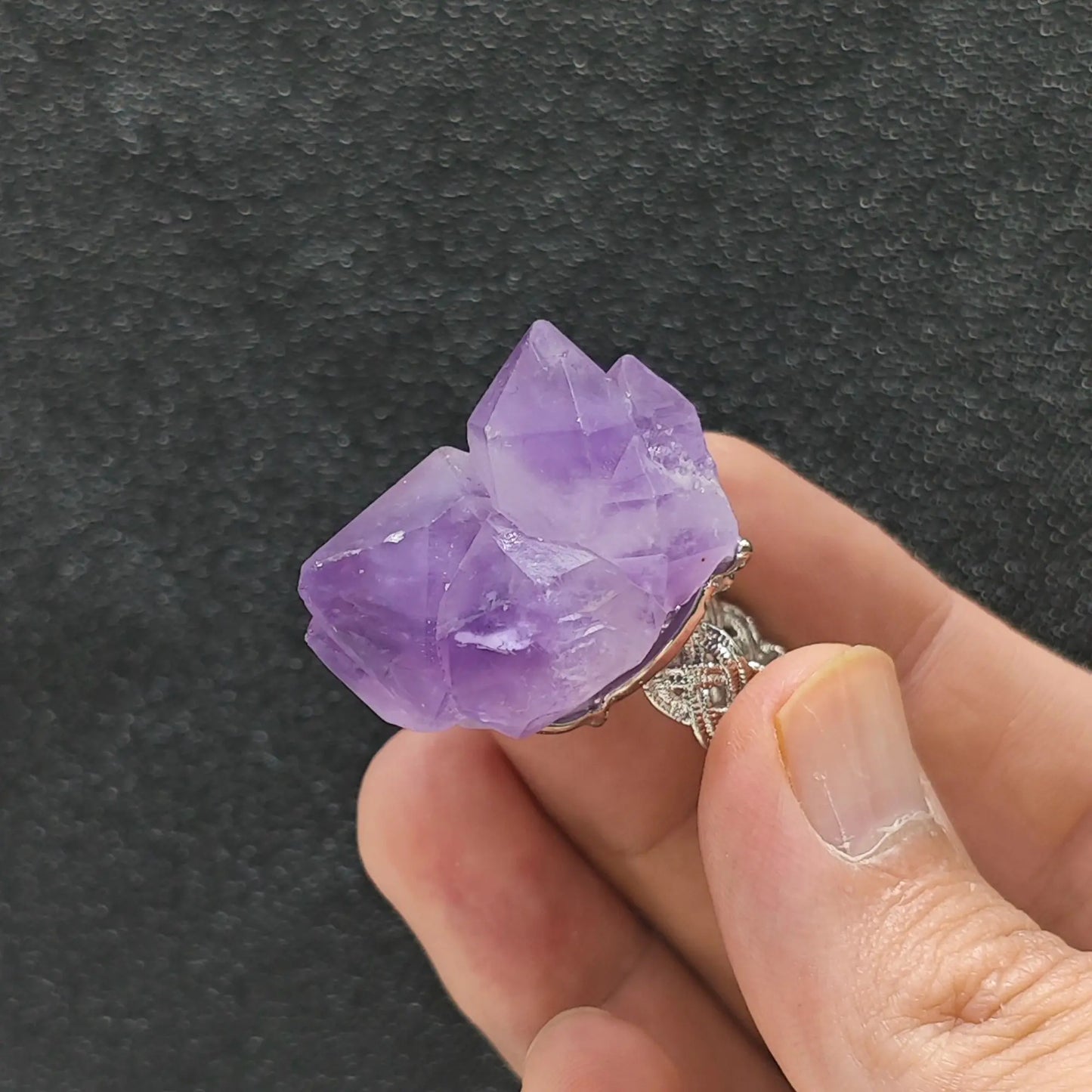 Large point amethyst crystal cluster adjustable alloy ring held in hand displaying prominent purple quartz termination points