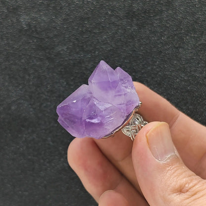 Large point amethyst crystal cluster adjustable alloy ring held in hand displaying prominent purple quartz termination points