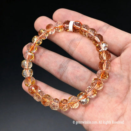 Top down view of a light golden quartz stretch bracelet showing faceted bead reflections against hand