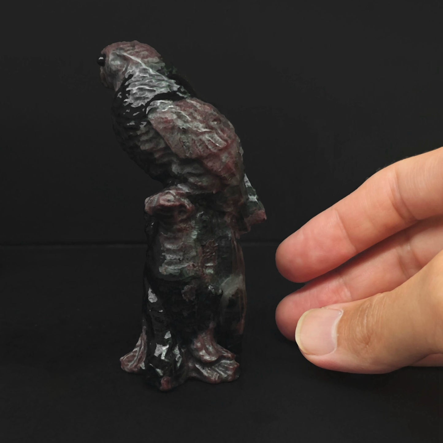 Back view of the hand sculpted red brown stone parrot statue highlighting detailed wings and sturdy stump base