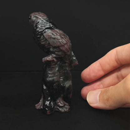 Back view of the hand sculpted red brown stone parrot statue highlighting detailed wings and sturdy stump base