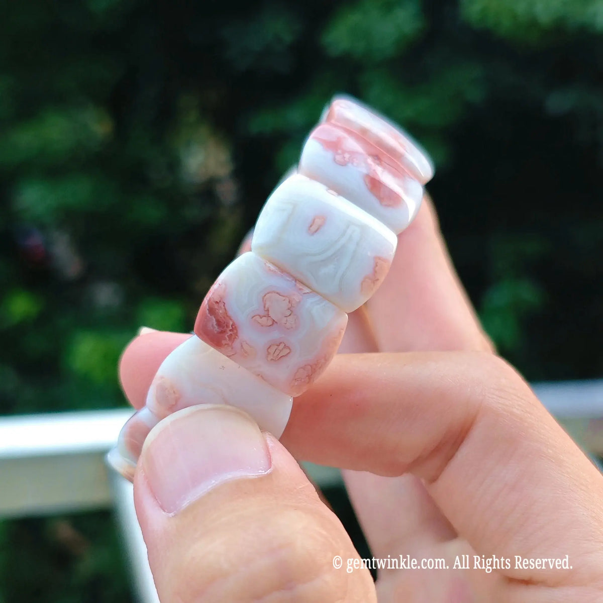 Close up view of pastel pink chalcedony flat bead strand showing translucent creamy mineral layers