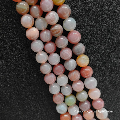 Vertical strands of pastel pink and lilac yanyuan agate beads highlighting excellent uniform spherical polish
