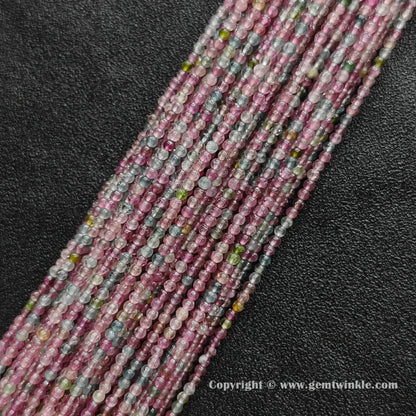 Multiple strands of pastel light color tourmaline 2.5mm micro round beads on dark background