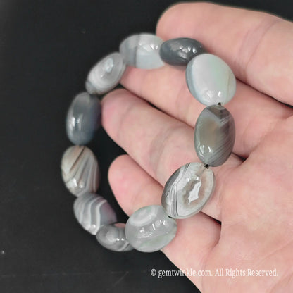 13-15mm grey banded persian agate oval bead stretch bracelet displayed in open hand