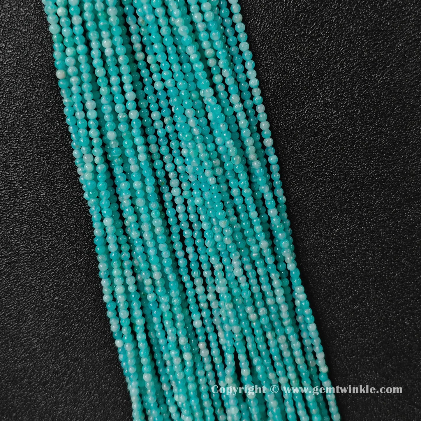 Vertical strand arrangement of petite aqua-cyan natural amazonite 3mm round beads displaying smooth polish