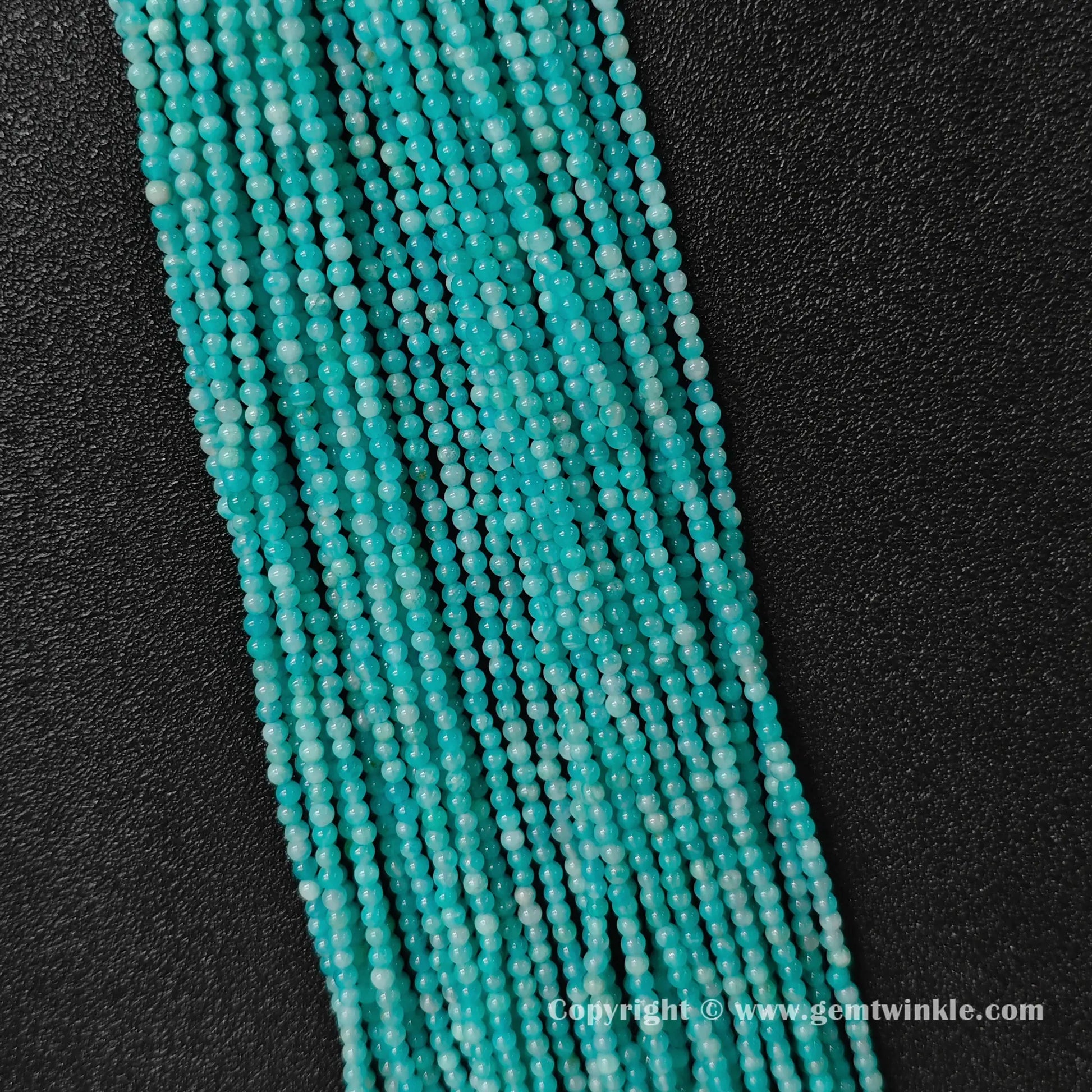 Vertical strand arrangement of petite aqua-cyan natural amazonite 3mm round beads displaying smooth polish
