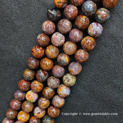 Angled view of Grade C pietersite round bead strands laid parallel on dark textured surface