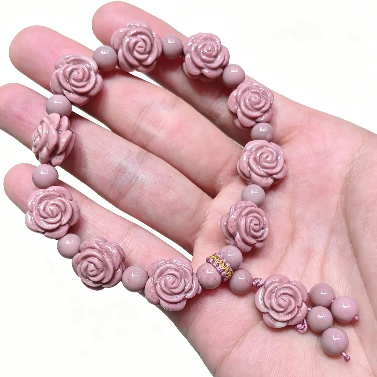 Handheld view of pink Alashan Gobi agate bracelet featuring carved rose beads and dangle charm