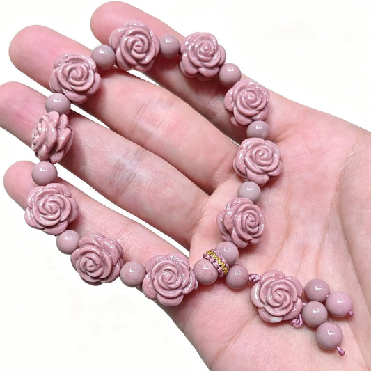 Handheld view of pink Alashan Gobi agate bracelet featuring carved rose beads and dangle charm