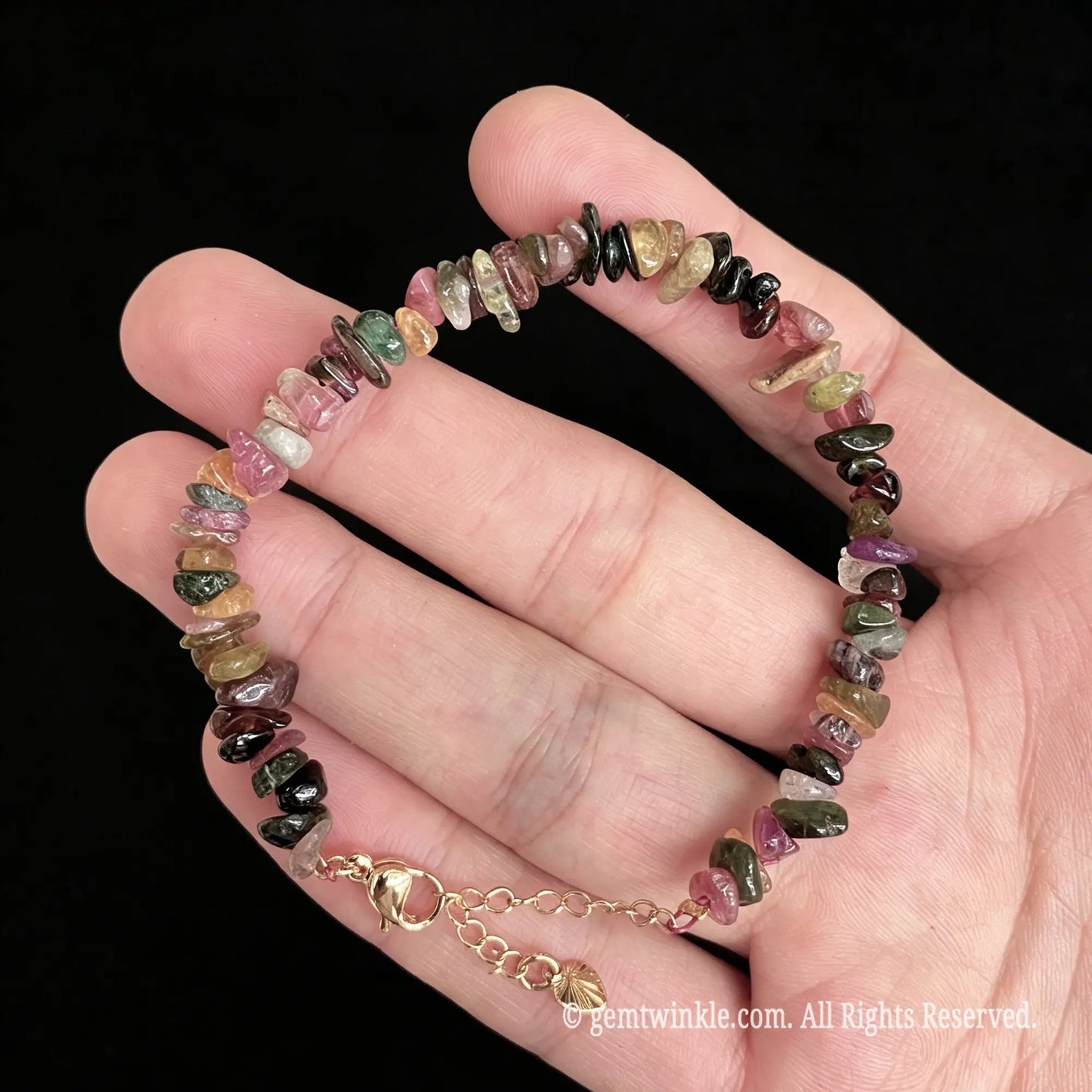 pink and green tourmaline chip bracelet resting on palm showing natural bead layout
