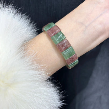  Woman wearing a Natural Pink & Green Strawberry Quartz Bangle Bracelet on her wrist, paired with a white fur coat, highlighting the bracelet's fit and style.