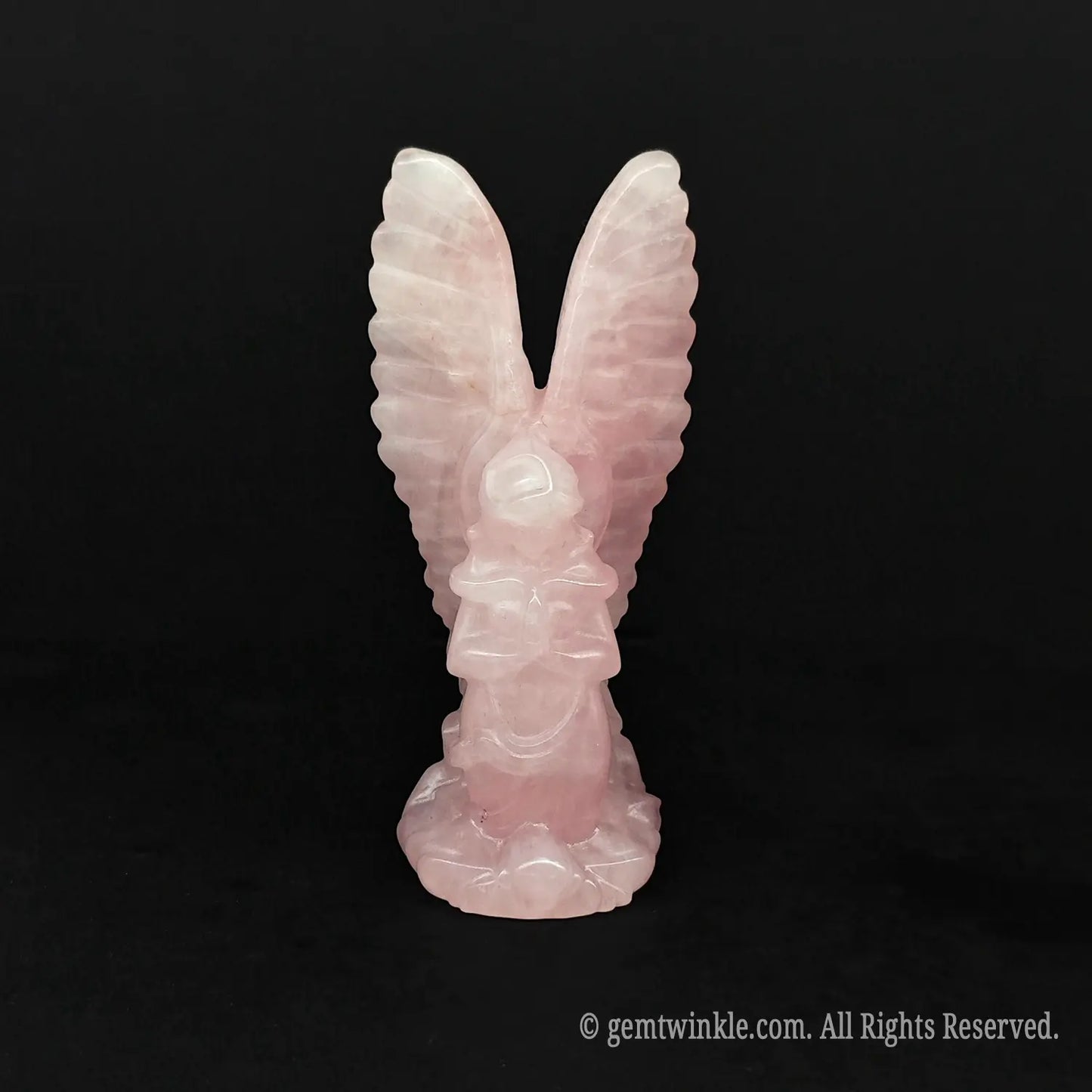Front view of a hand carved pink opal archangel figurine with high reaching wings on a dark background