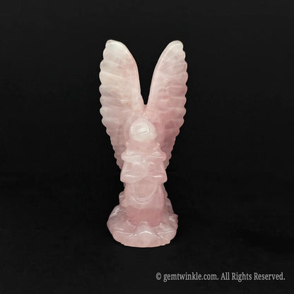 Front view of a hand carved pink opal archangel figurine with high reaching wings on a dark background