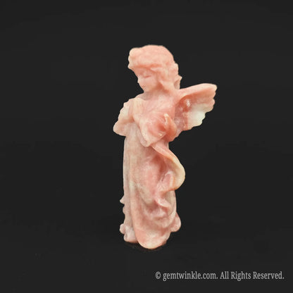 Side profile view of a natural pink opal guardian angel crystal statue showing detailed feather carving and a smooth matte texture
