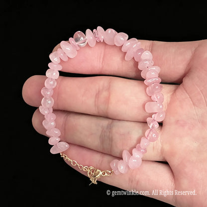 pink rose quartz chip bracelet resting flat on open hand displaying beaded structure