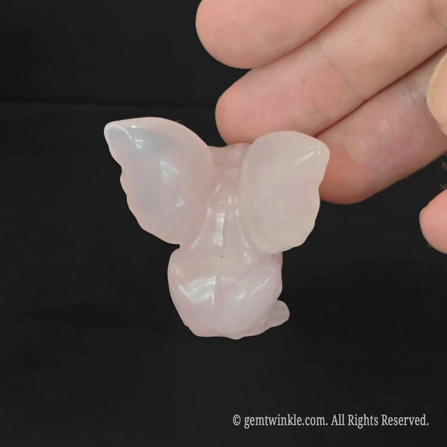 Back view of carved rose quartz gargoyle figurine highlighting outspread wing structure