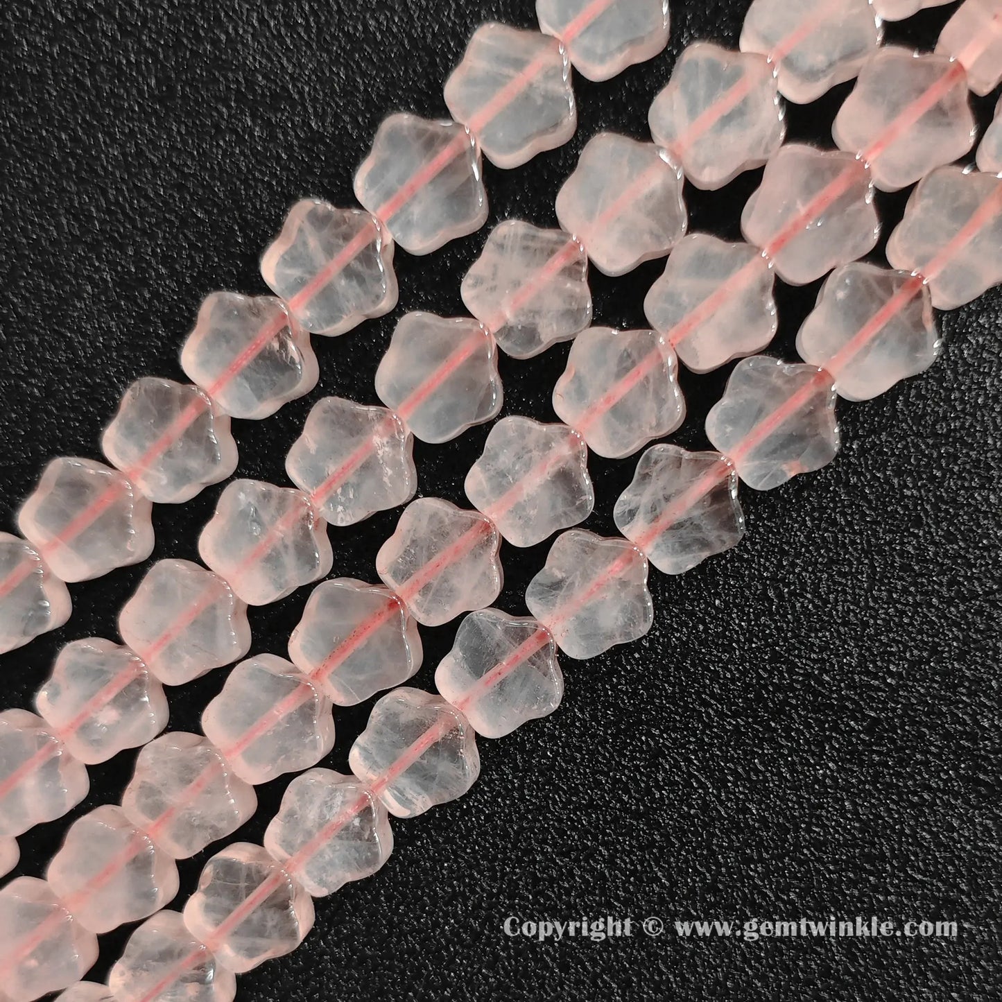 Angled view of natural pastel pink rose quartz star carved gemstone strands