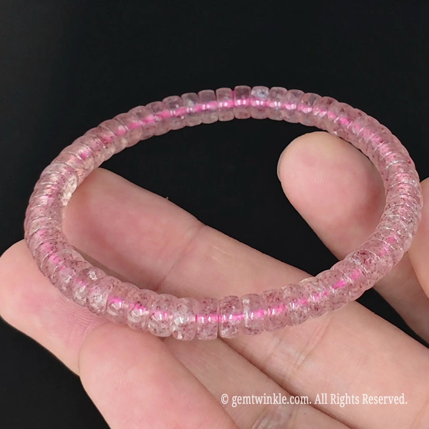 close up of translucent pink strawberry quartz disc bead strand in hand