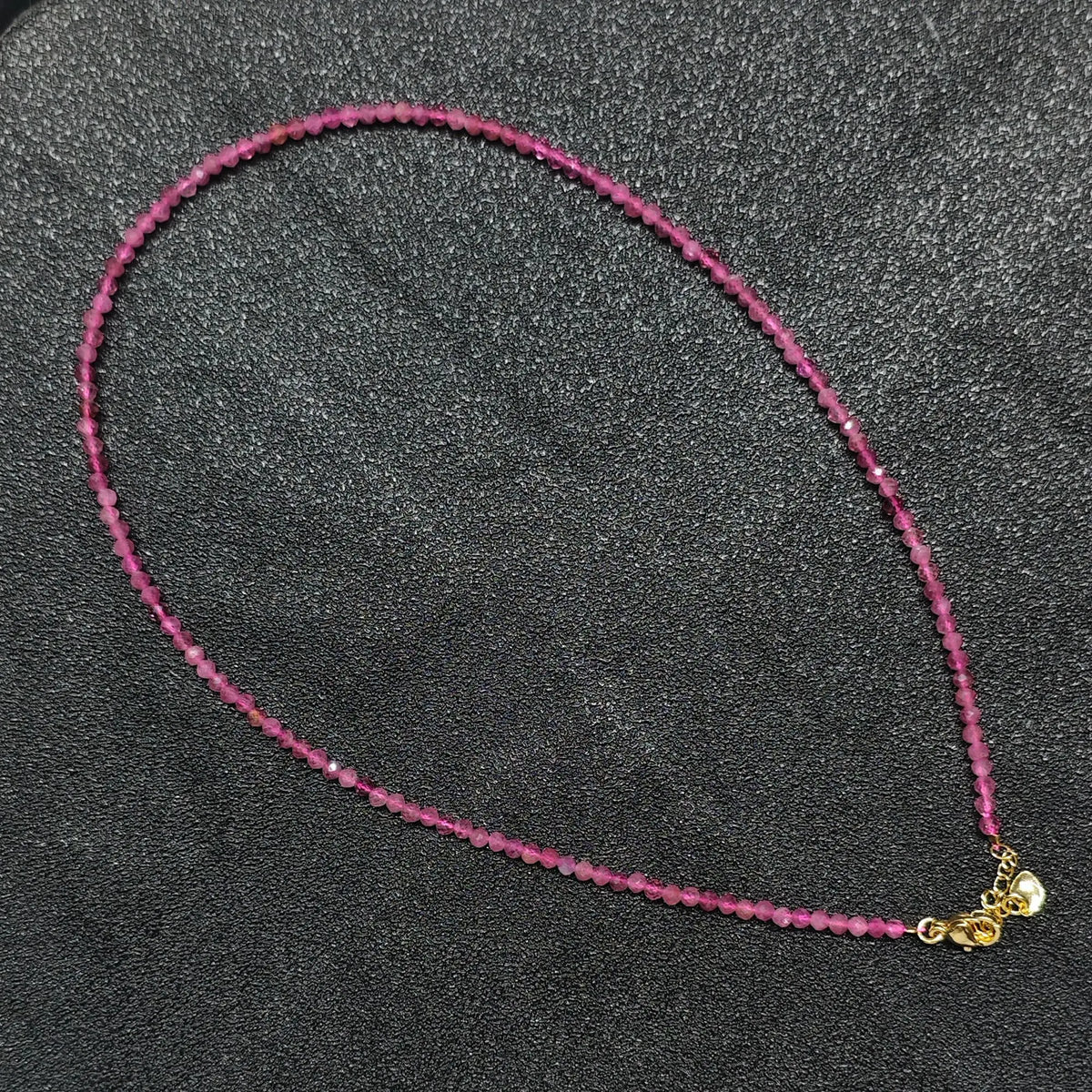 Hand holding 3mm faceted pink tourmaline necklace showing vibrant magenta tones for boutique resellers