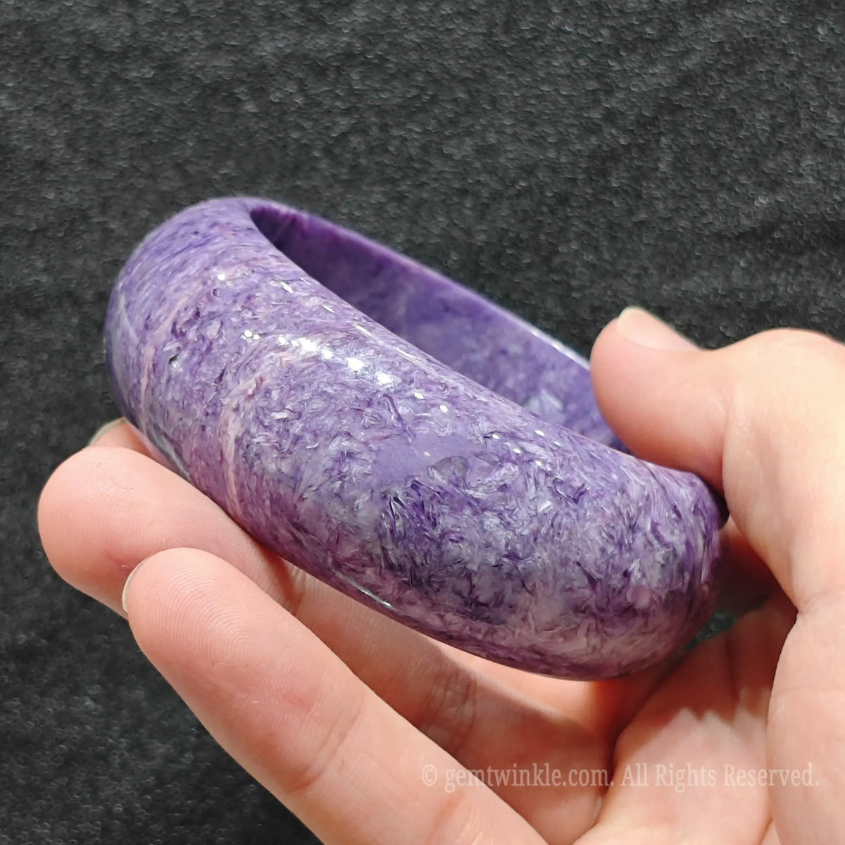 hand demonstrating smooth outer curve and luster of charoite bracelet