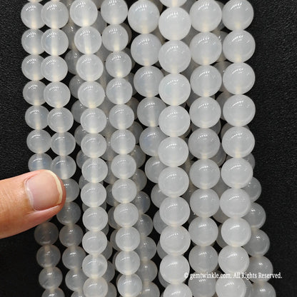 Inspecting multiple strands of porcelain white agate beads held in hand for scale and clarity check