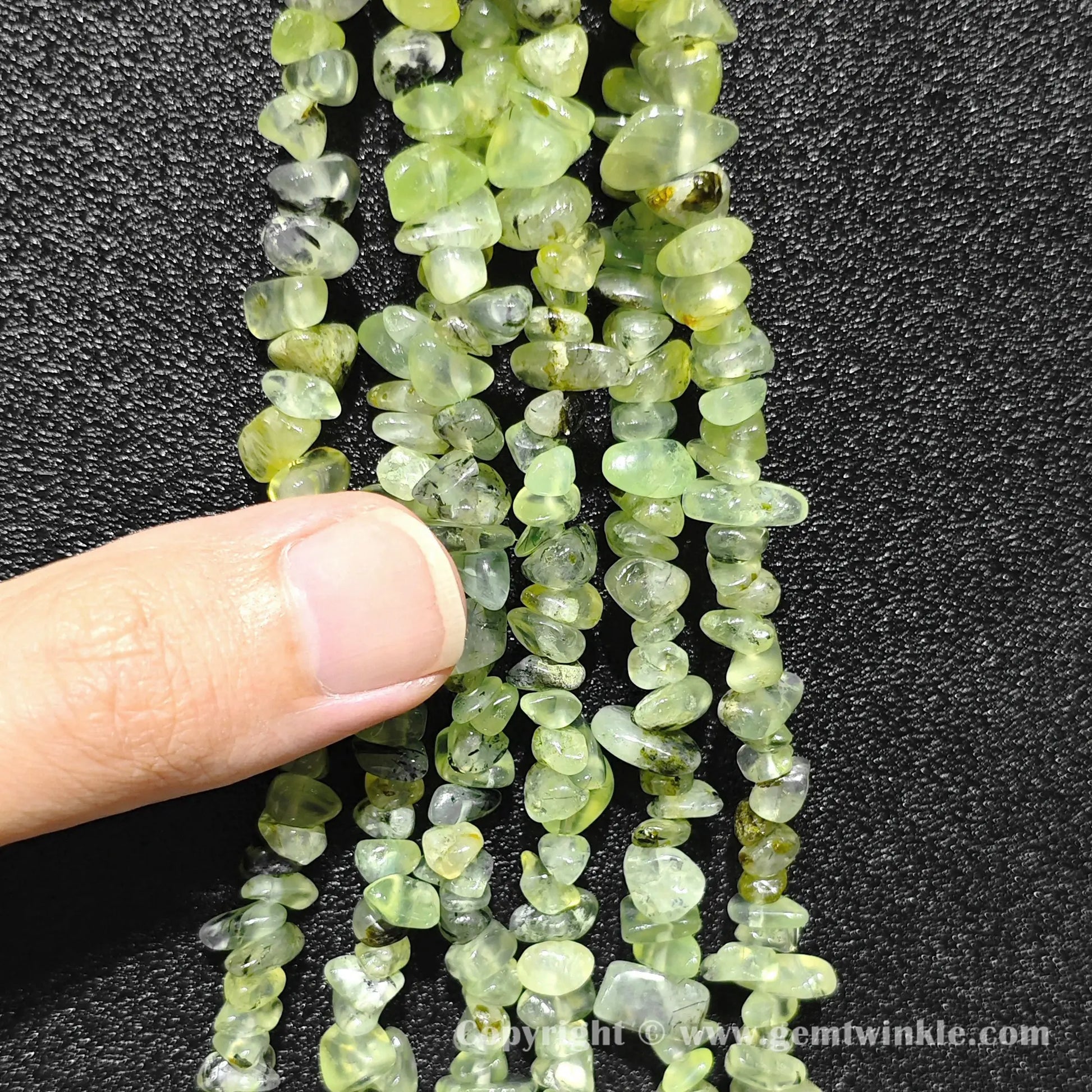 Hand holding 75cm continuous strand of natural prehnite irregular chip beads