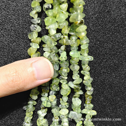 Hand holding 75cm continuous strand of natural prehnite irregular chip beads
