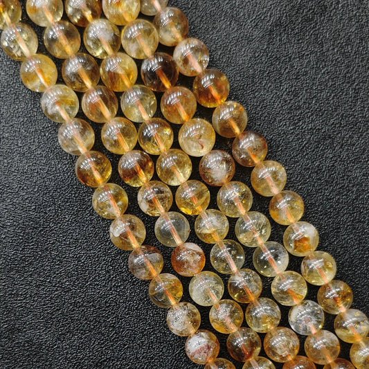 Diagonal close up view of high clarity grade b plus heat treated citrine phantom quartz loose beads showing bright translucent amber tones